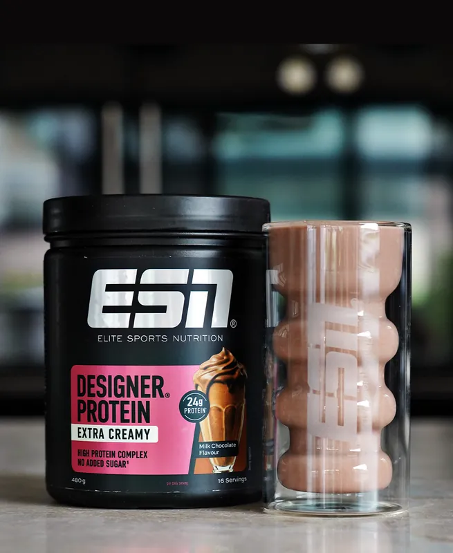 ESN Designer Protein Extra Creamy – Milk Chocolate, con un vaso