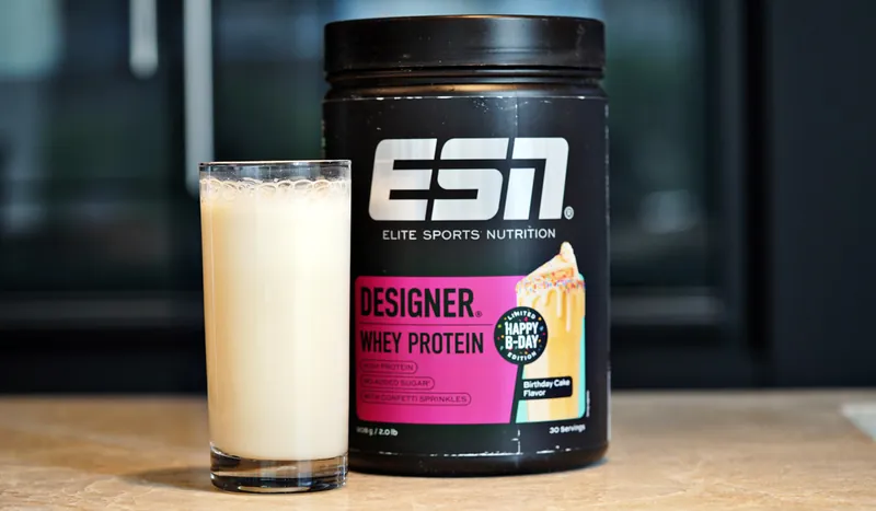 ESN Designer Whey Protein – Birthday Cake, con un vaso